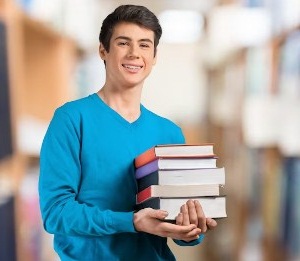 Joven con libros en una biblioteca. becas ingenieria en sistemas