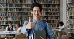 Joven en la biblioteca con libros en las manos. Becas medicina